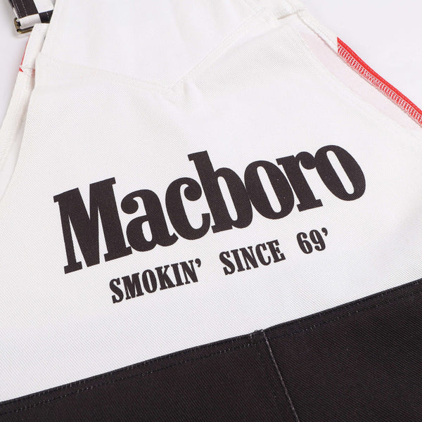 Close-up of Macboro Overalls with "Smokin' Since 69'" text print on white fabric showing strength, grit, and endurance.