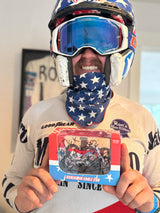 Ronnie Mac wearing motocross gear holds a signed Screamin Eagle bike replica with a personalized message.