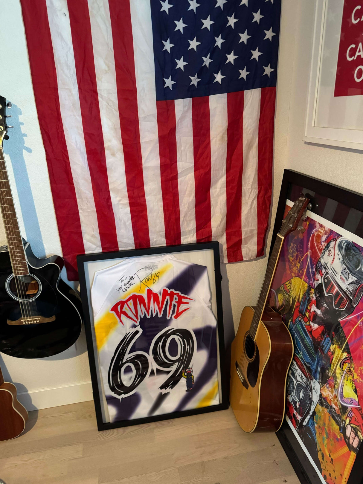 Ronnie Mac autographed jersey framed, displayed with an American flag and guitars in a sports memorabilia collection.