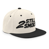 "2 Still Smoking embroidered snapback hat with flat brim and structured design featuring bold black lettering on cream fabric"