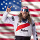 Man in patriotic headband and sunglasses poses with American flag backdrop, embodying American pride and style.